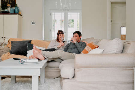 Forget the world and just connect. a couple having wine while relaxing on the sofa at home.