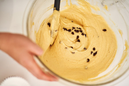 Chocolate chips fixes everything. an unrecognizable woman mixing batter in a glass bowl.