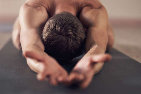 Let the zen take over. an unrecognizable man stretching and practicing yoga indoors.