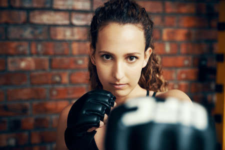Ill kick some butt if I have to. Cropped portrait of a female kick boxer practicing at the gym.の写真素材