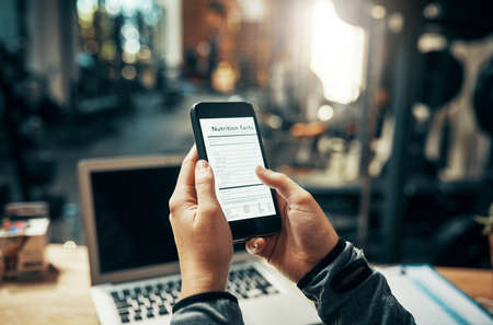 I want to introduce my members to this application. an unrecognizable woman using her cellphone while sitting at her desk.の写真素材