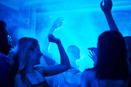 a crowd of people dancing inside of a club at night.