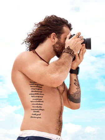 Collect as many memories as you can. a young man taking pictures with his camera at the beach.