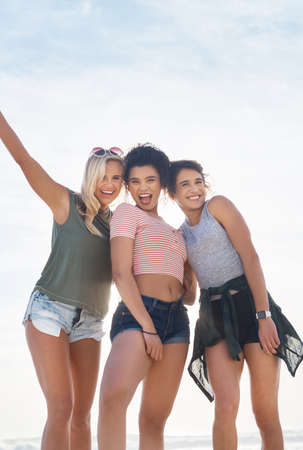 You wont find us anywhere else in summer. three friends spending the day at the beach.の写真素材