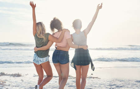 At the beach is where youll find us. three friends spending the day at the beach.の写真素材