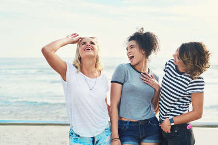 No one is as entertained by us like us. three friends spending the day together on a sunny day.の写真素材