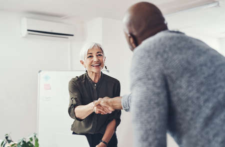 Im excited to get working with you. two cheerful businesspeople shaking hands in agreement inside of the office during the day.の写真素材