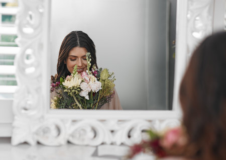 This is going to be an amazing day. a beautiful woman smelling flowers while sitting in front of the mirror.の写真素材