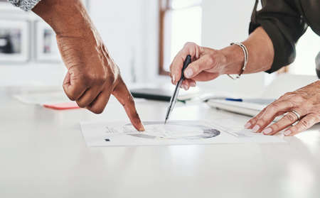 Right there. two unrecognizable businesspeople working together on paperwork in their office.の写真素材