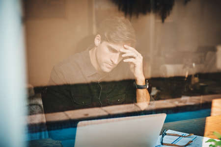 Failure is sometimes apart of the bigger plan. a young businessman looking stressed out while working on a laptop in his office at home.の写真素材