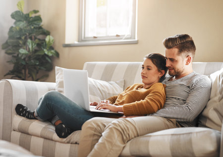 I dont see any listings that I like, babe. a young couple using a laptop while relaxing at home.の写真素材