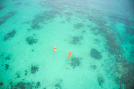 The ocean called, we answered. High angle shot of two adventurous young couples canoeing together in the beautiful oceans of Indonesia.の写真素材