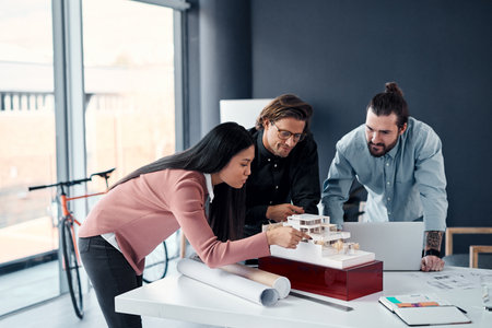 This project needs all of our expertise. three young architects working on a scale model of a modern house in their office.の写真素材