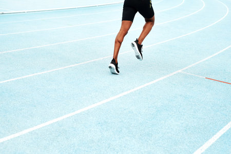 Building up my strength for the race. an unrecognizable athlete running along a track field alone during an outdoor workout session.の写真素材