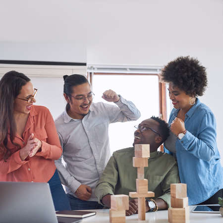 Forward thinkers make success flourish. a group of young businesspeople having a meeting with building blocks in a modern office.の写真素材