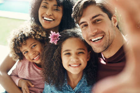 a beautiful young family taking a selfie together outdoors.