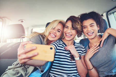 These are the moments we cherish the most. young women taking a selfie while out on a road trip together.の写真素材
