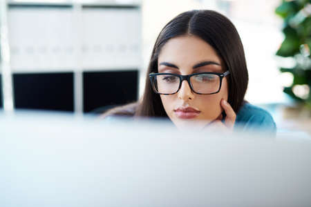 Work hard so you can achieve greatness. a young businesswoman working on a computer in an office.の写真素材