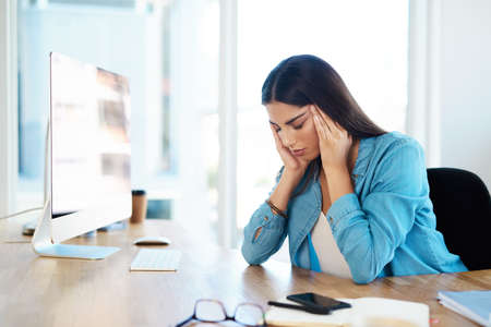 Stress is one of the main triggers of tension headaches. a young businesswoman looking stressed out...