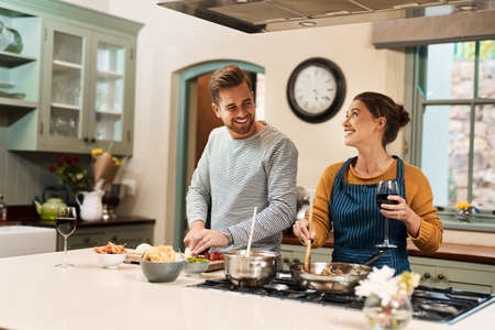 Guess which dessert I have in mind. an affectionate young couple cooking together in their kitchen at home.の写真素材