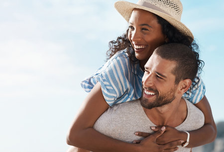 What a blissful day out together. a young man piggybacking his girlfriend at the beach.の写真素材