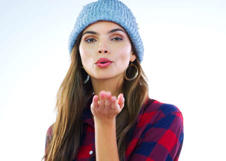 It always starts with a simple kiss. a beautiful young woman blowing kisses against a white background.の写真素材