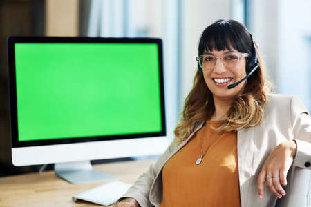 I am in my comfort zone here at work. Cropped portrait of an attractive young businesswoman sitting and using a headset in her office during the day.の写真素材