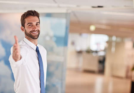 What an honour it is to be working with you. Portrait of a young businessman extending a handshake in an office.の写真素材
