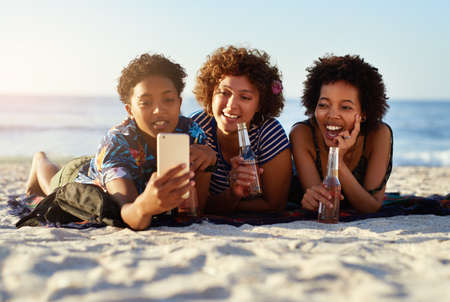 Lets remember this moment forever. an attractive young trio of women laying down on the beach and...