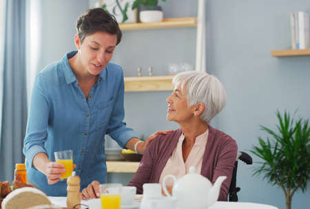Orange juice is the best for you. a happy senior woman sitting and having breakfast with her attractive young daughter while at home.の写真素材