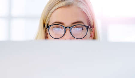 Glued to the screen. a focused young businesswoman working on her computer inside of the office.の写真素材