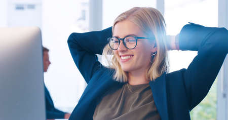 Sit back and enjoy the ride. a carefree young businesswoman sitting back in her chair and taking a break inside of the office.の写真素材
