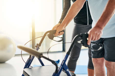 Each delicate step counts. an unrecognizable female physiotherapist helping a senior man use a walker in a fitness centre.の写真素材