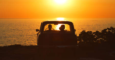 Forgetting the world for a while. Rearview shot of two unrecognizable girl friends sitting in a vehicle while on a road trip at the beach.の写真素材