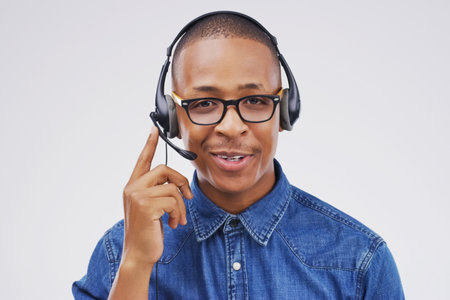 Hes dedicated to his customers. Studio portrait of a handsome young male customer service representative wearing a headset against a grey background.の写真素材