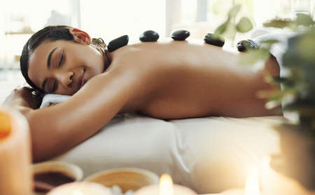 This is the most relaxing treatment. a young woman getting a hot stone massage at a spa.の写真素材