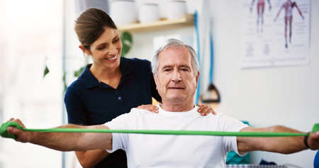 Hes doing a great job. an attractive young female physiotherapist working with a senior male patient.の写真素材