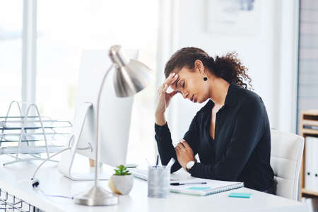 How many more challenges do I have to face today. a young businesswoman looking stressed out while working in an office.の写真素材
