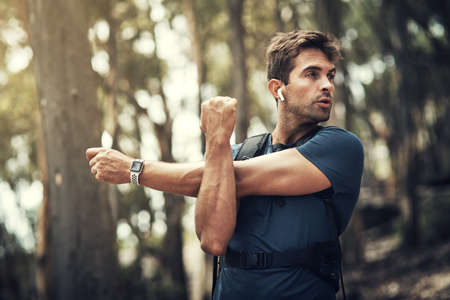 Getting ready for a hike. a handsome young man stretching before heading off on his hike in the...