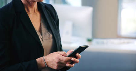 Connecting with colleagues and clients. Closeup shot of a businesswoman texting on a cellphone in an office.の写真素材