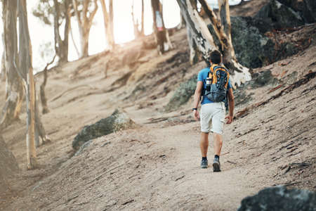 I have some walking to do. a carefree young man going for a hike up a mountain outside during the day.の写真素材