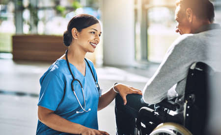 She knows just how to brighten a patients day. a friendly medical practitioner assisting a handicapped patient.の写真素材