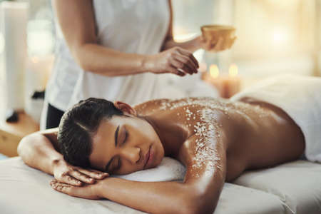 Salt scrubs impart a natural glow to the skin. a young woman getting an exfoliating massage at a spa.の写真素材