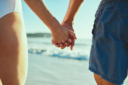 All s well when youre by my side. Closeup shot of a couple holding hands at the beach.の写真素材