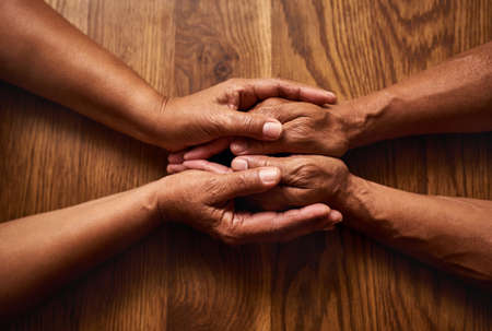 The bond we share can never be broken. High angle shot of an unrecognizable senior couple holding hands together over a wooden table at home.の写真素材