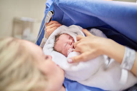 Shell be running around the house in no time. an adorable baby girl sleeping in her mothers arms in hospital.の写真素材