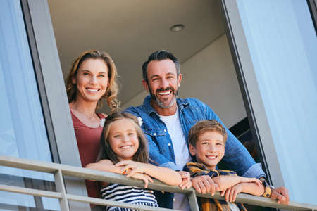 Things are looking up for us. Portrait of a happy young family standing on the balcony of their home.の写真素材