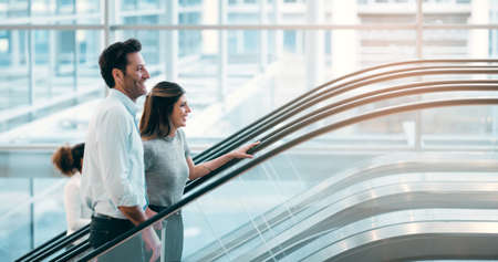 Theyre excited about working together. two young businesspeople going up an escalator in a modern...