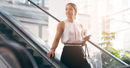 Shes pleased with how far shes come. an attractive young businesswoman looking thoughtful while going down an escalator in a modern workplace.の写真素材