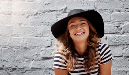 Sunny days in the city are always the best. Portrait of an attractive young woman posing against a brick wall outdoors.の写真素材